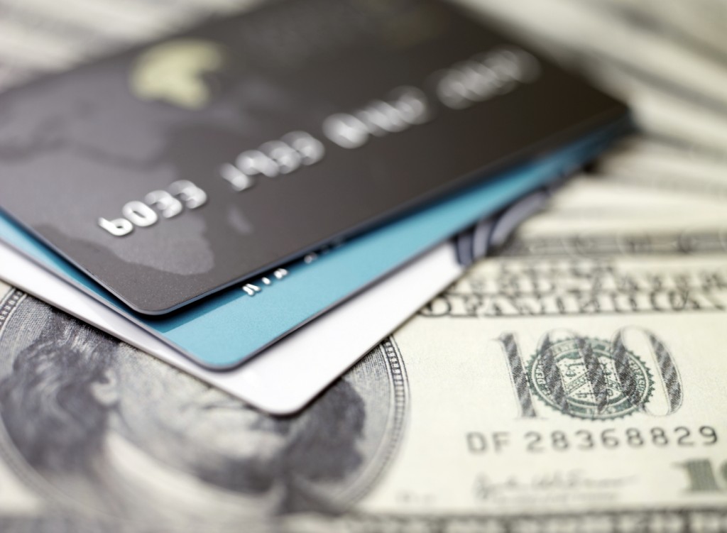 Stack of credit cards on US dollar bills suggesting hidden family assets and financial investigation