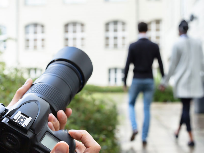 Private investigator photographing a couple during a cheating spouse surveillance investigation