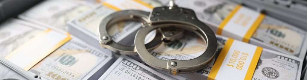 Handcuffs on stacks of cash symbolizing loss prevention and fraud investigations by Tristar private investigator California