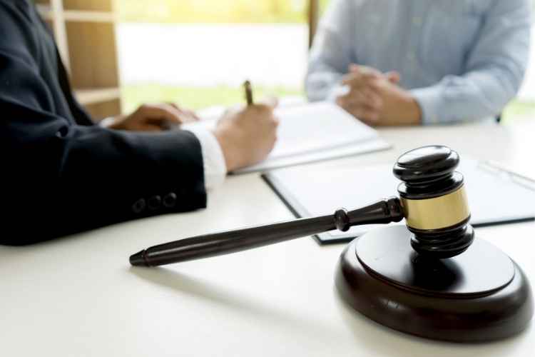 Gavel on desk with attorney consulting client over paperwork — missing plaintiff investigation support for attorneys