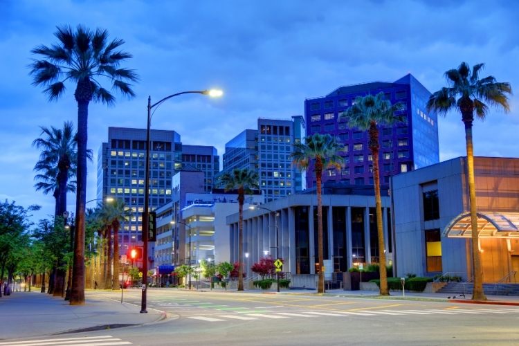 Downtown San Jose at dusk, quiet street with office buildings, palm trees, and lit windows