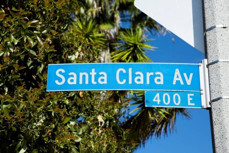 Blue 'Santa Clara Av 400 E' street sign on pole with palm trees and clear sky, Santa Clara County
