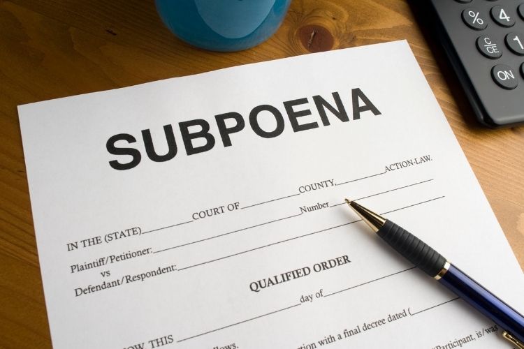 Subpoena form on wooden desk with pen, calculator and mug — Tristar subpoena service in California