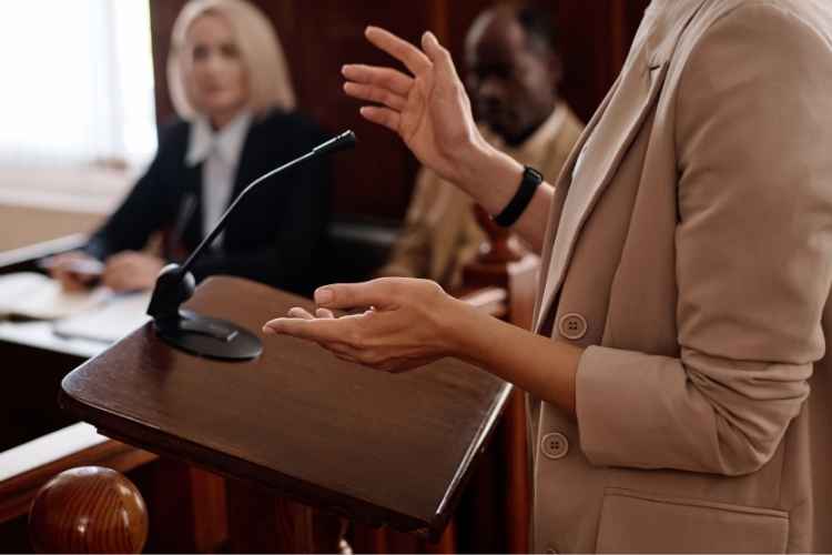 Attorney speaking at a courtroom podium during witness outreach, illustrating PAGA employee list research