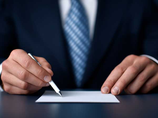 Hands of a suited professional holding a pen over a document for workers' comp case paperwork