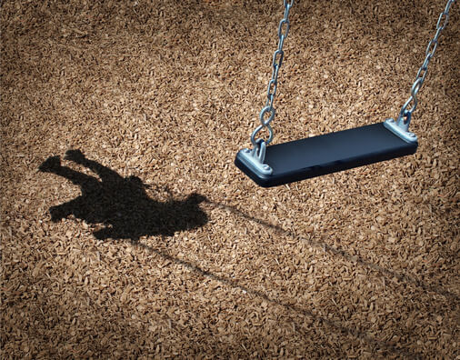 Empty playground swing and child's shadow on mulch, evoking a missing child search
