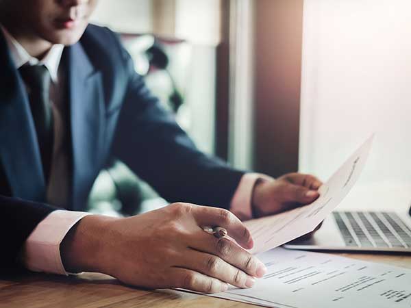 Investigator in suit reviewing claimant documents by laptop, background checks for insurance claims