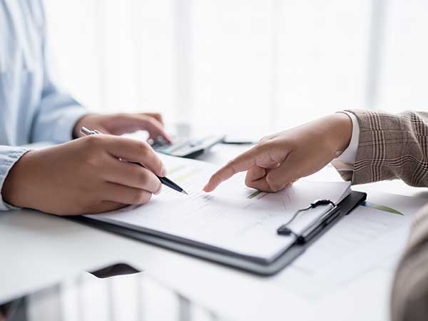 Two professionals reviewing a candidate file on a clipboard, one pointing while the other annotates — background checks