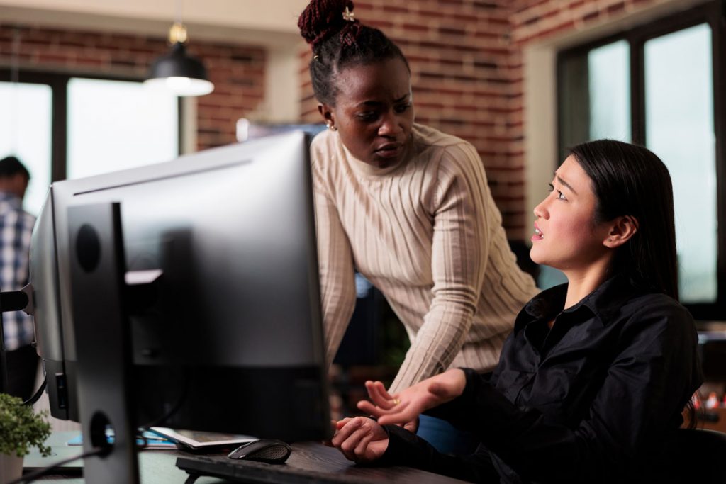 Manager and employee reviewing records on a computer during a workplace interview