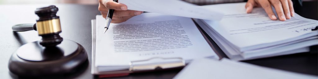 Gavel beside hands reviewing legal documents before filing a lawsuit