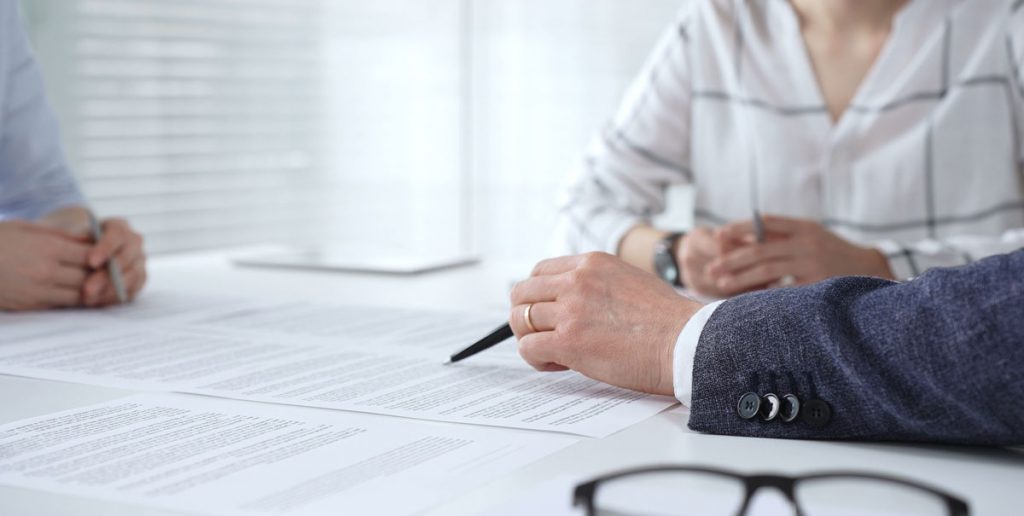 Attorneys and a client reviewing contracts across a conference table