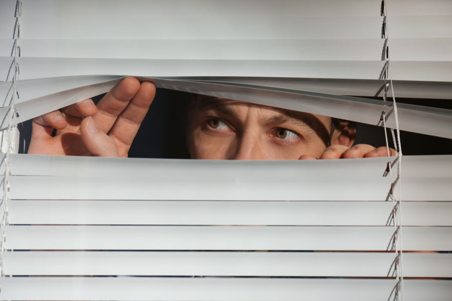 Man peering through window blinds instead of answering the door to a process server