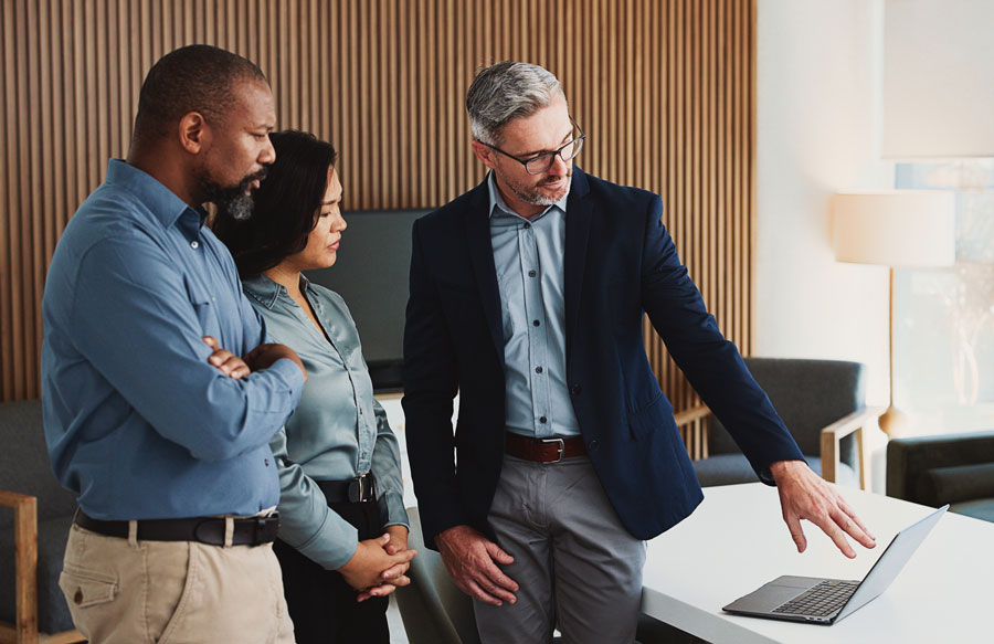 Attorney reviewing a case file on a laptop with two colleagues in an office